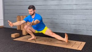 Male yoga instructor demonstrates cossack squat pose