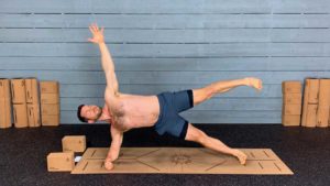 Male Yoga Instructor Posing in Side Plank with Leg Raised