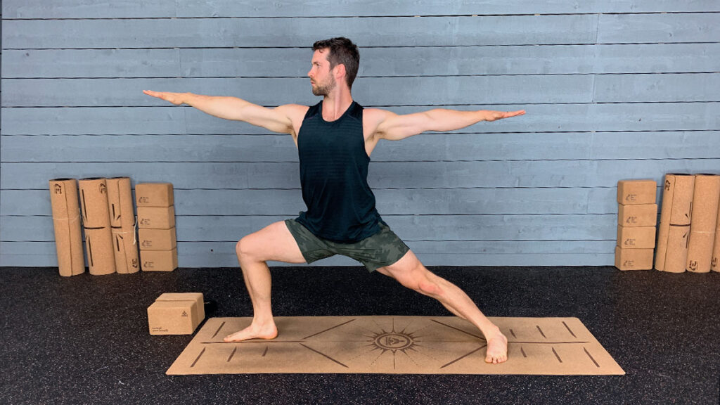 male yoga instructor demonstrates warrior 2 pose as part of morning yoga routine