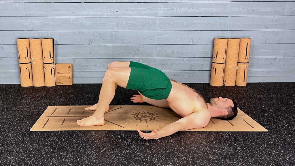 Shirtless male yoga instructor demonstrating bridge pose