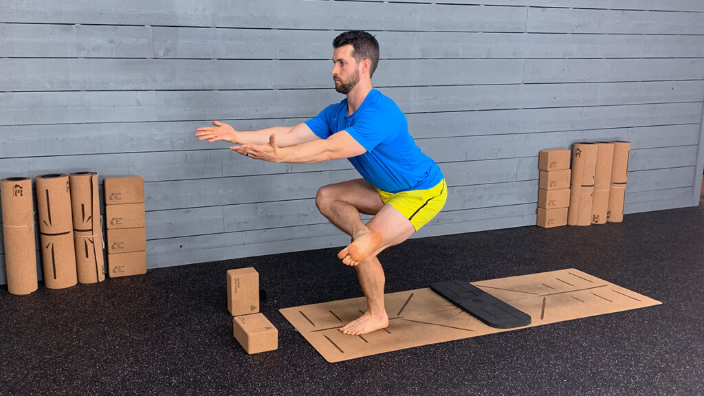 Male yoga instructor demonstrates figure four squat pose