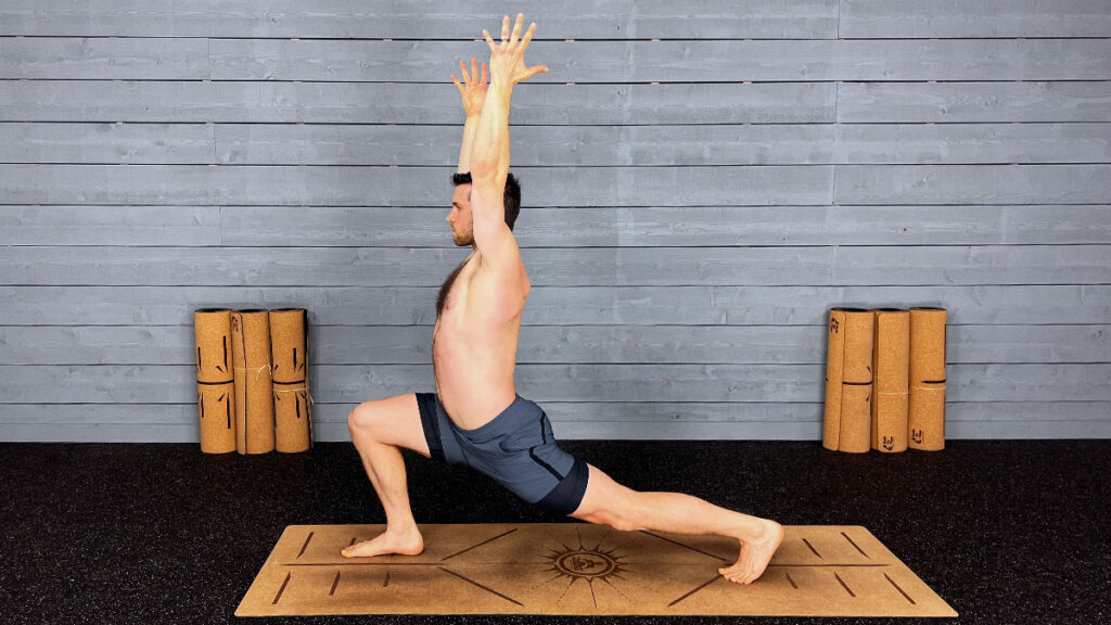 shirtless male yoga instructor demonstrates high lunge pose with arms overhead