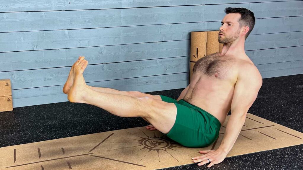 Shirtless male yoga instructor demonstrating boat pose and doing yoga exercises for hips