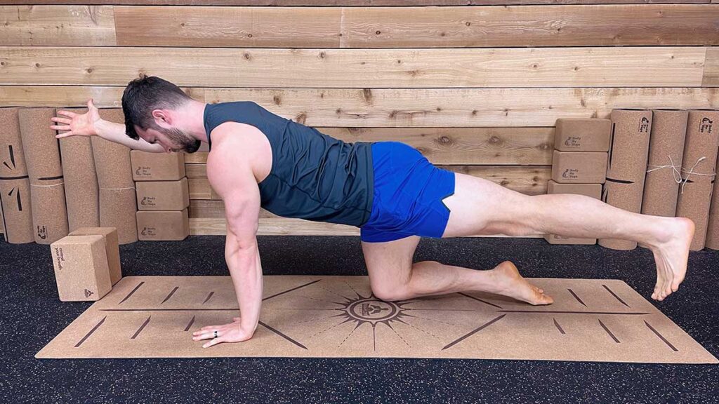 Male yoga instructor demonstrating bird dog pose to strengthen knees