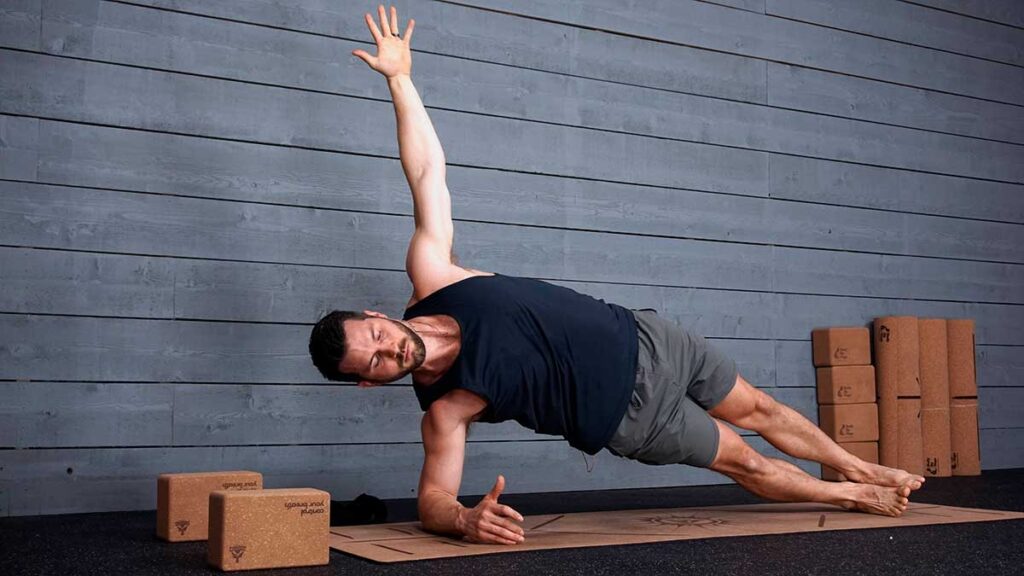 Male yoga instructor demonstrating side plank pose to help with knee pain