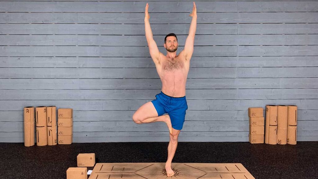 Shirtless male yoga instructor demonstrating tree pose for yoga for knee pain workout