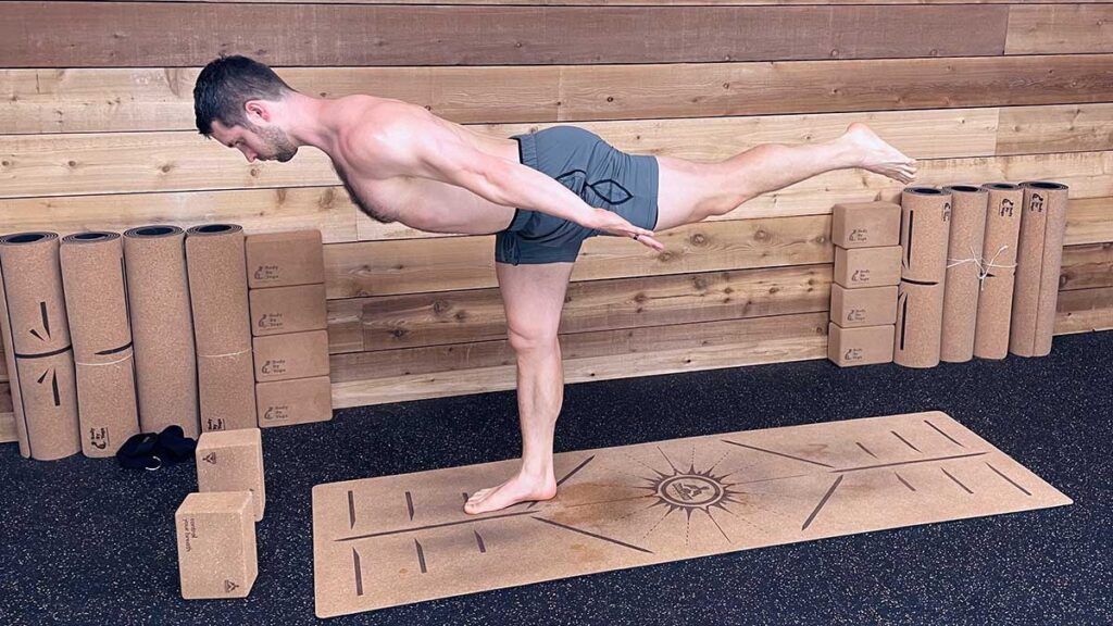 Shirtless Male Yoga Instructor demonstrating airplane pose for yoga for knee pain workout