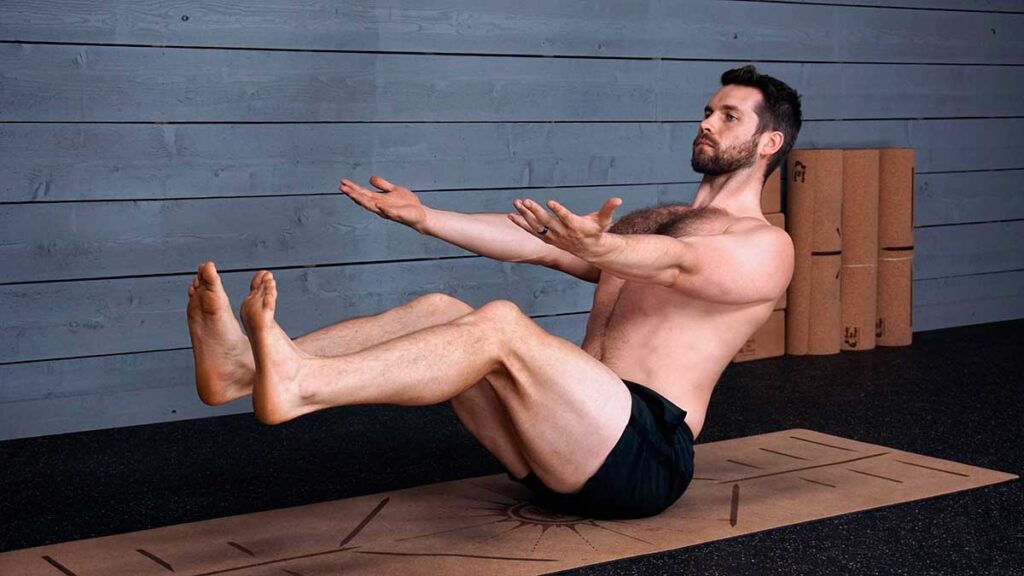 Shirtless male yoga instructor demonstrating boat pose for yoga for knee pain workout