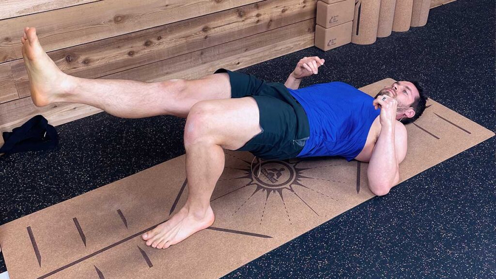 Male Yoga Instructor demonstrates single leg bridge pose to help with knee pain