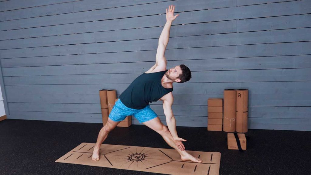 Male yoga instructor demonstrates triangle pose