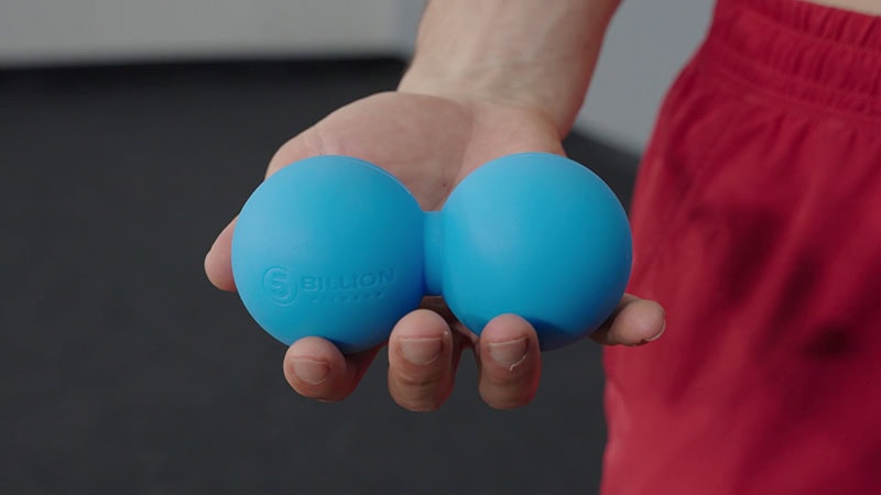 Man holding blue massage balls for mobility and flexibility exercises.